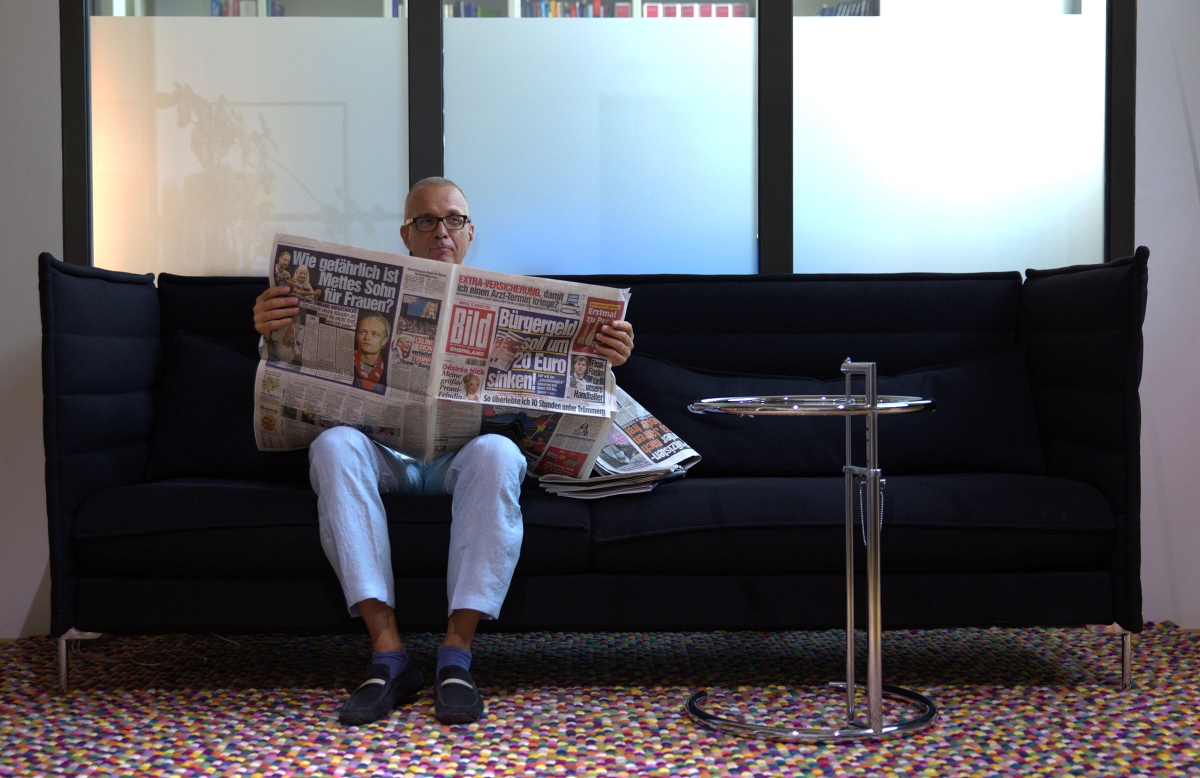 Jörg Pfannenberg auf dem Sofa mit einer Zeitung.